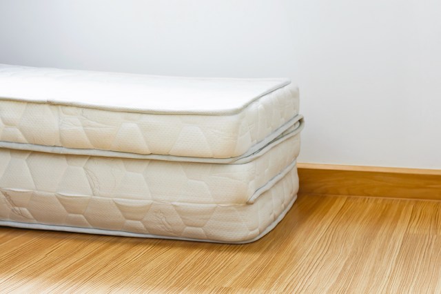 A photo of a trifolding mattress shot according to the rule of thirds. The mattress is bare and on a wood floor against a white wall.