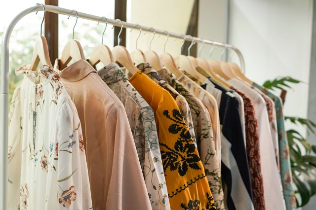 A white metal garment rack holding different silky-looking blouses.