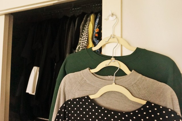Three long-sleeve shirts on hangers that are connected by soda tabs to make use of vertical space in a closet.