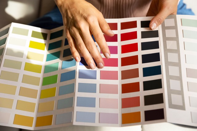 Anonymous person with their hand on a paint company's color brochure, scanning the options.